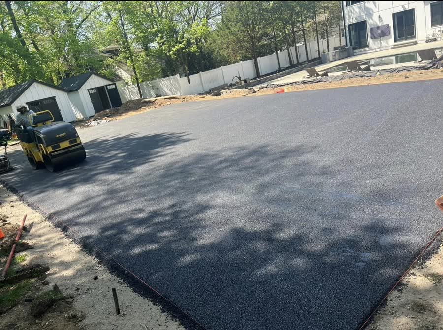 Crew rolling fresh asphalt on a parking pad